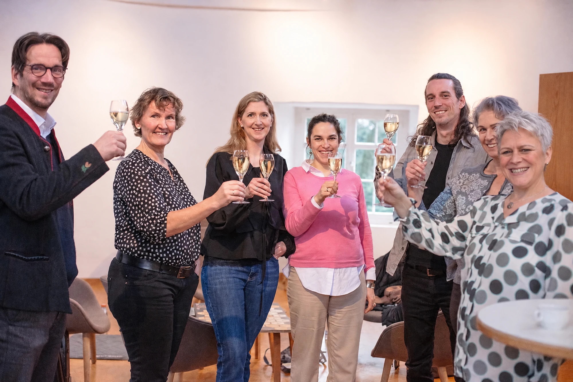 Stefanie Aufleger und eine Workshopgruppe beim gemeinsamen Anstoßen. KI-aktualisiertes Originalmotiv.