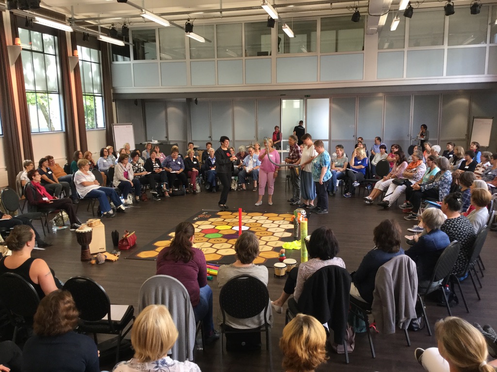 Workshopgruppe im großen Stuhlkreis rund um ein STEAUF-Spielfeld.